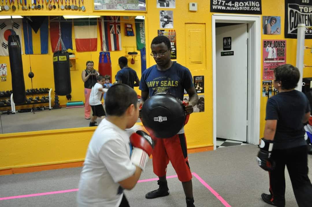 Roy Wayne coaching a youth boxer with a body shield